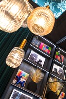 A modern interior with hanging glass lamps, framed artwork, and decorative elements on shelves.