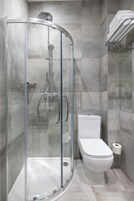 Ein modernes Badezimmer mit einer Glaskabine zur Dusche, einer weißen Toilette und einem Handtuchhalter.