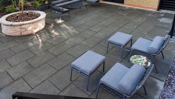 An outdoor patio area with a brick wall, a black metal fence, and a seating arrangement including a table and chairs.