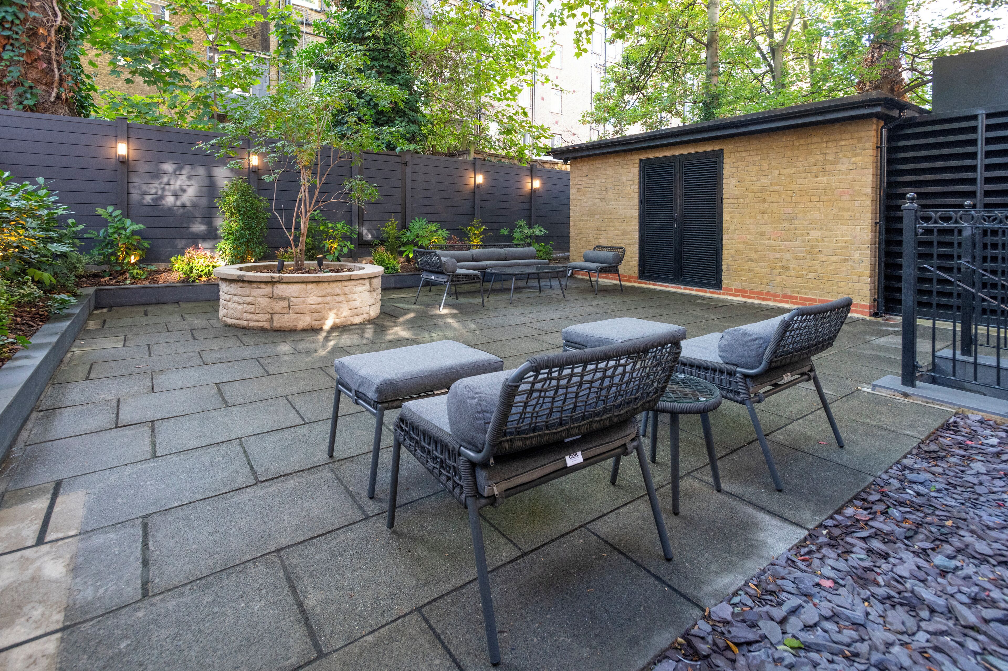 A patio with stone flooring, outdoor furniture, and a brick wall.