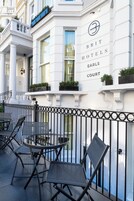 Exterior de un hotel británico con una fachada clásica, un balcón con asientos y un llamativo letrero del hotel.