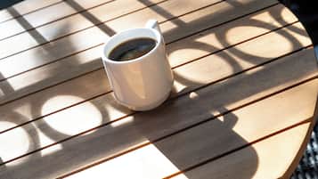 A white mug of coffee on a wooden table with a grid pattern.