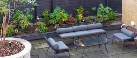 A patio with a grey sofa set, a small round table, and a metal chair.
