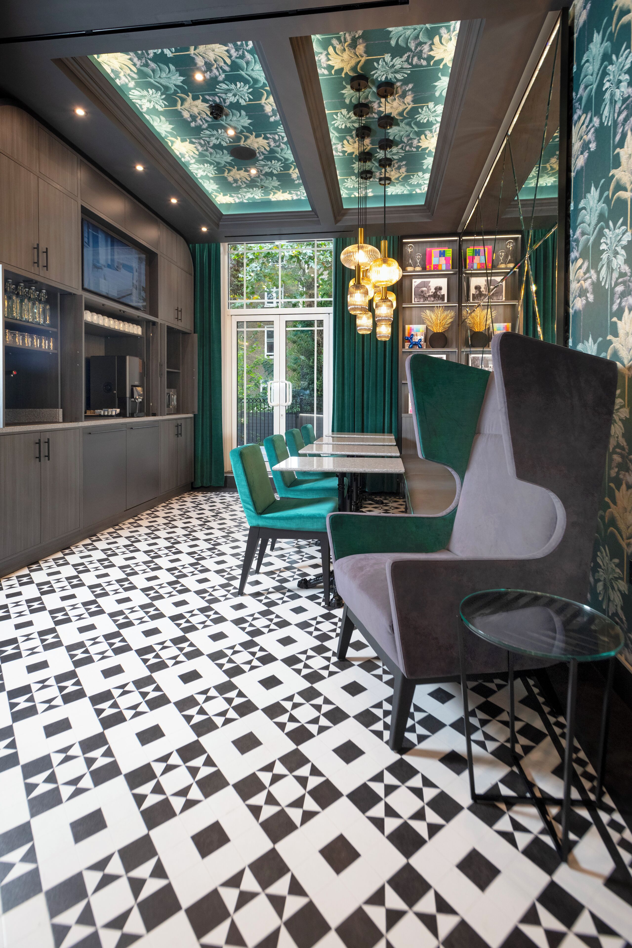 Un interior moderno con suelo de diseño geométrico, una zona de comedor con sillas color turquesa y un techo con motivos florales.