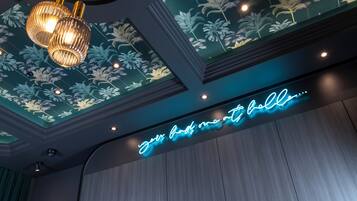 A ceiling with a floral pattern and a neon sign that reads "Your home to hell."