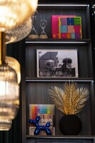 Ein Regal mit Dekorationsobjekten, darunter ein gerahmtes Foto, ein buntes Buch und eine blaue Skulptur.