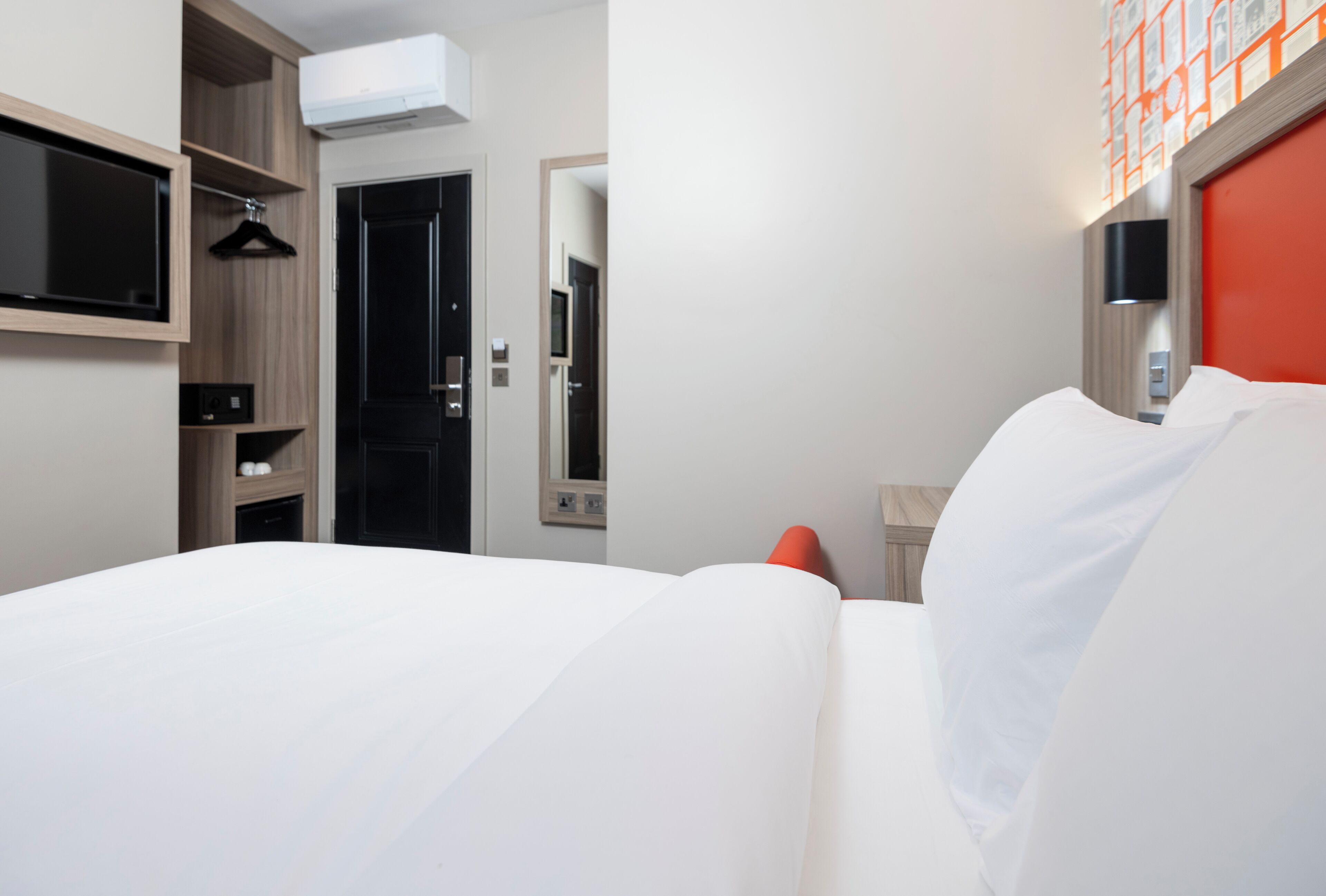 Une chambre d’hôtel équipée d’un lit, d’un téléviseur fixé au mur, d’une armoire et d’un miroir.