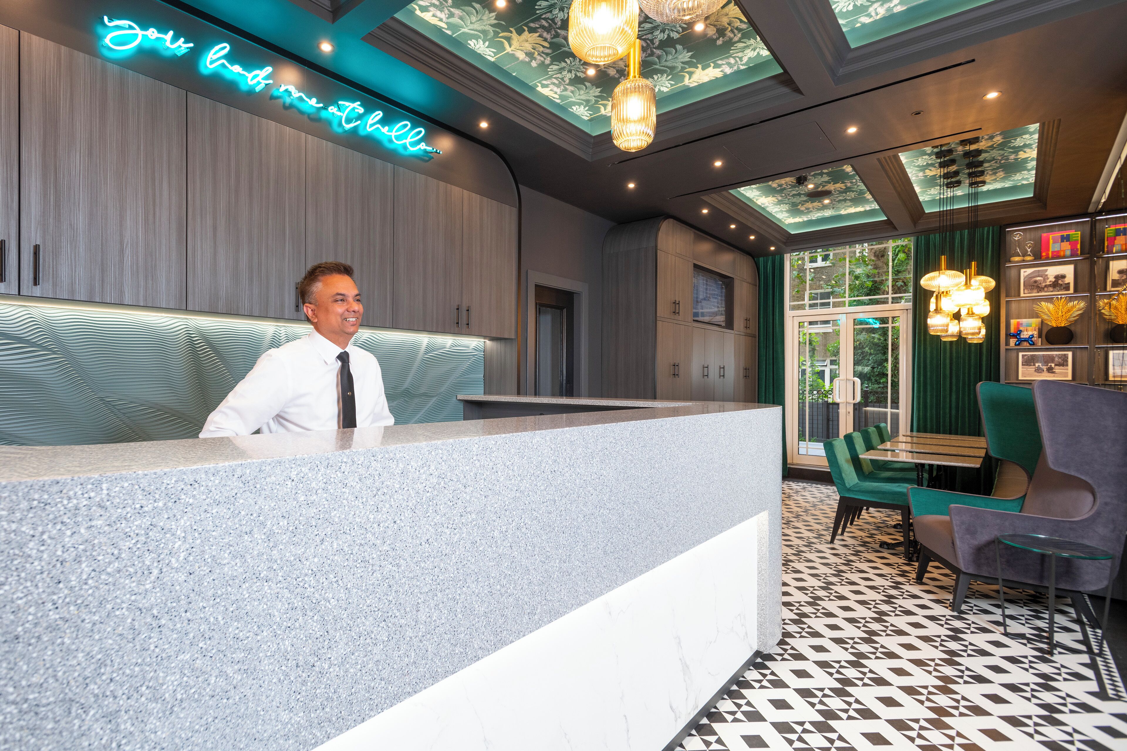 Una moderna hall d'hotel con reception, area salotto e illuminazione decorativa.