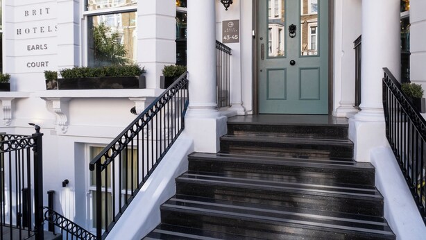 A grand entrance with a green door, white columns, and a staircase leading to the entrance. - Brit Hotels Earls Court (London)