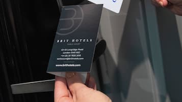 A hand inserting a key card into a key card reader at the entrance of a hotel.