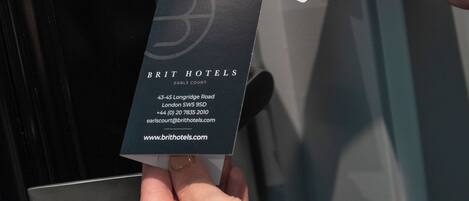 A hand inserting a key card into a key card reader at the entrance of a hotel.