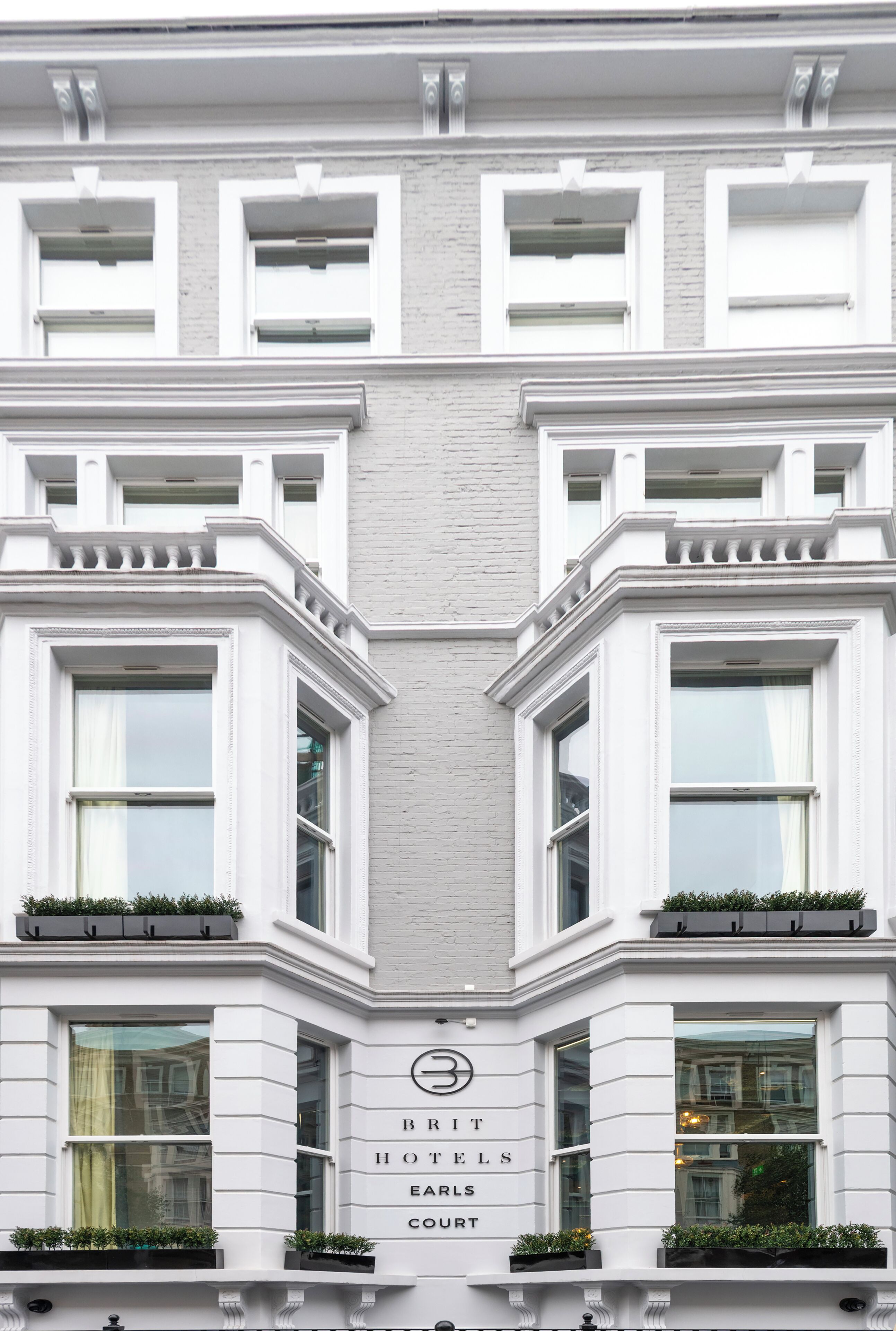 A building with a symmetrical facade, large windows, and a sign indicating it is a hotel.