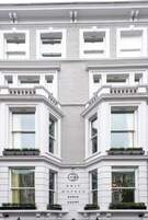 Ein Gebäude mit einer symmetrischen Fassade, großen Fenstern und einem Schild, das es als Hotel kennzeichnet.