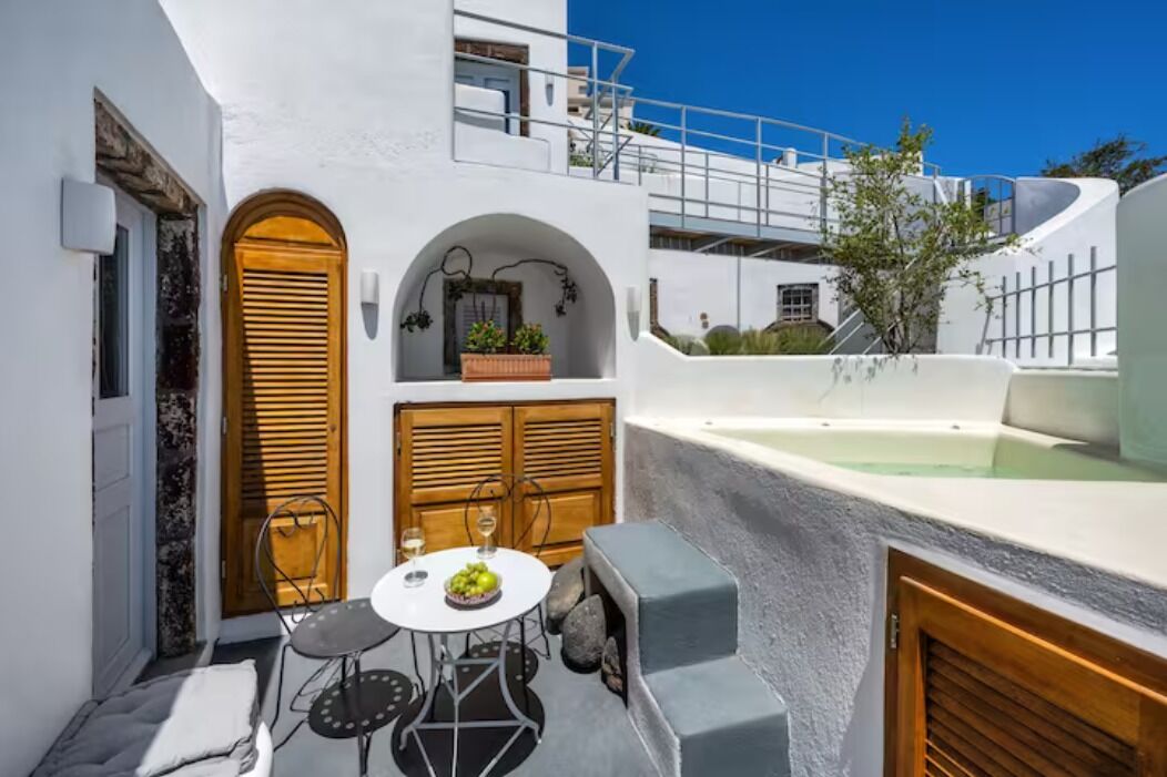A compact outdoor seating area with a table and chairs, a wooden door, and a small garden.