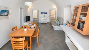 Una cocina moderna con comedor, paredes blancas y una zona de estar acogedora con cojines.