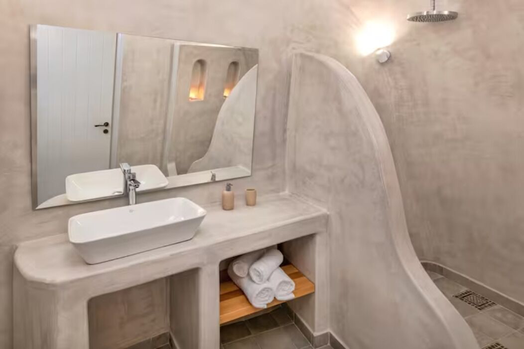 A bathroom with a white sink, mirror, and shower.