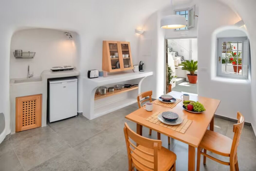 A compact kitchen with a built-in oven, a small refrigerator, and a wooden cabinet.