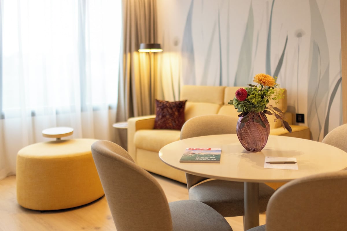 Un salon moderne avec une table ronde, un canapé et un vase rempli de fleurs.