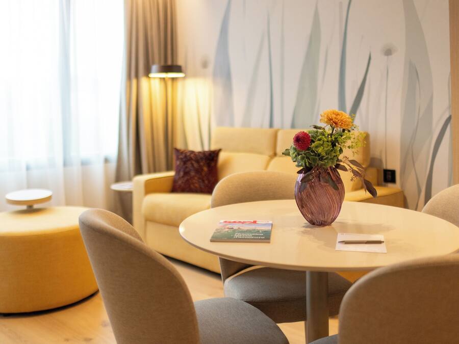 A modern living room with a round table, a sofa, and a vase with flowers.