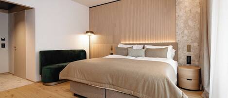 Un dormitorio moderno con una cama grande, una mesita de noche, una lámpara y una silla verde.