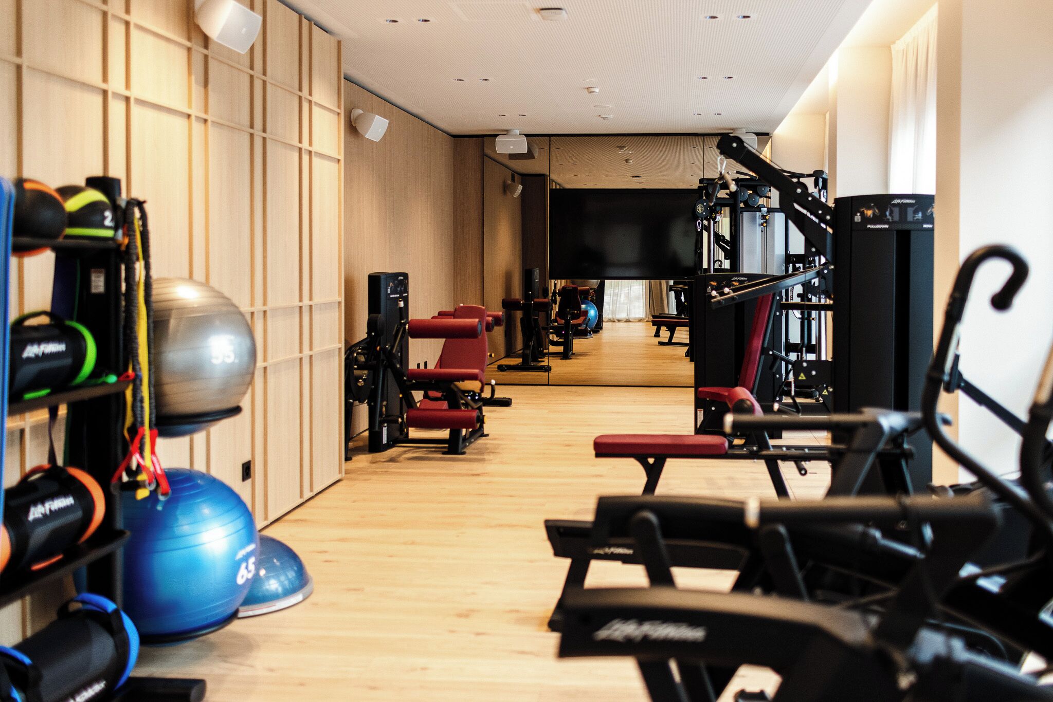 A gym with exercise equipment, a large mirror, and a television screen.