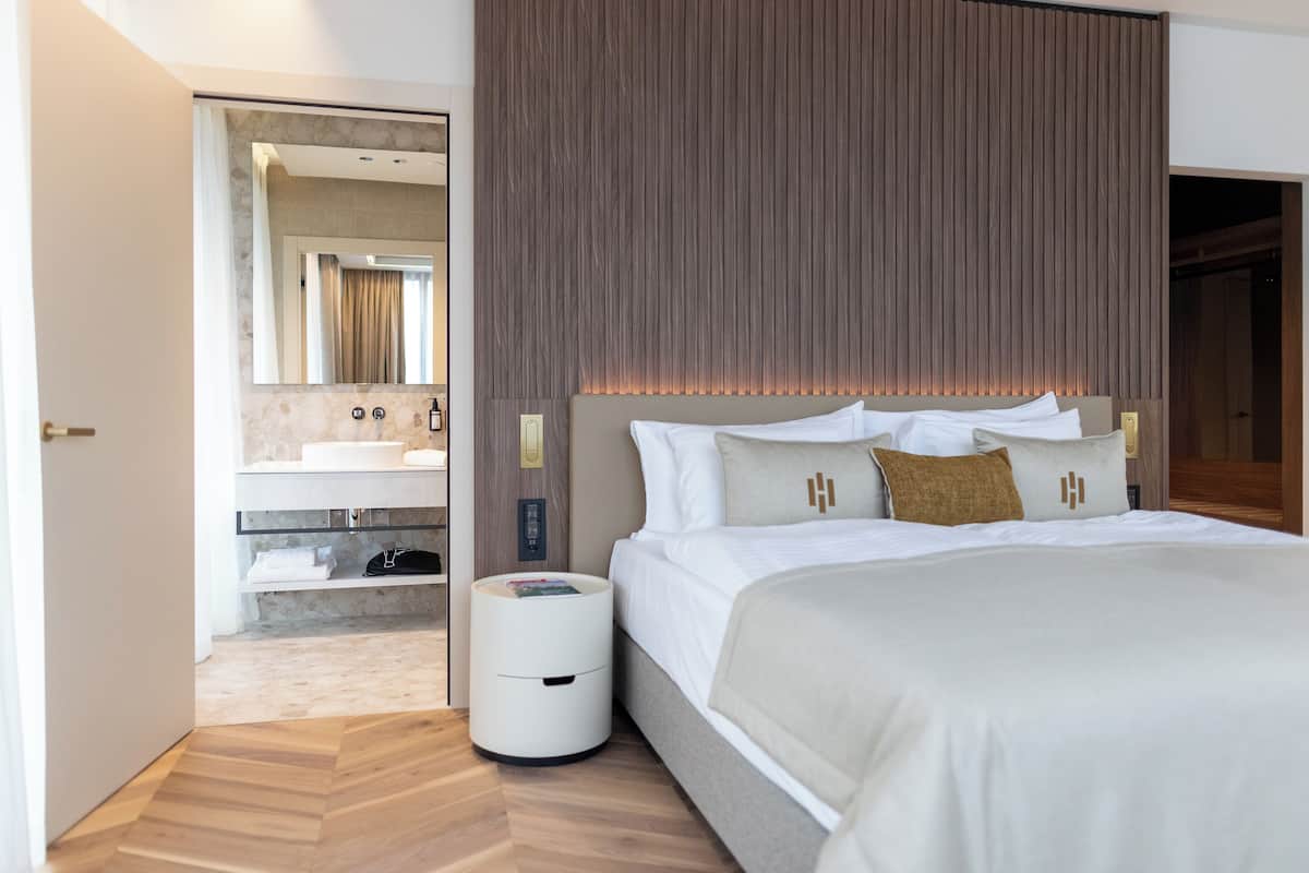 Une chambre d’hôtel moderne dotée d’un grand lit, d’une coiffeuse intégrée avec un miroir et d’un mur revêtu de panneaux en bois.