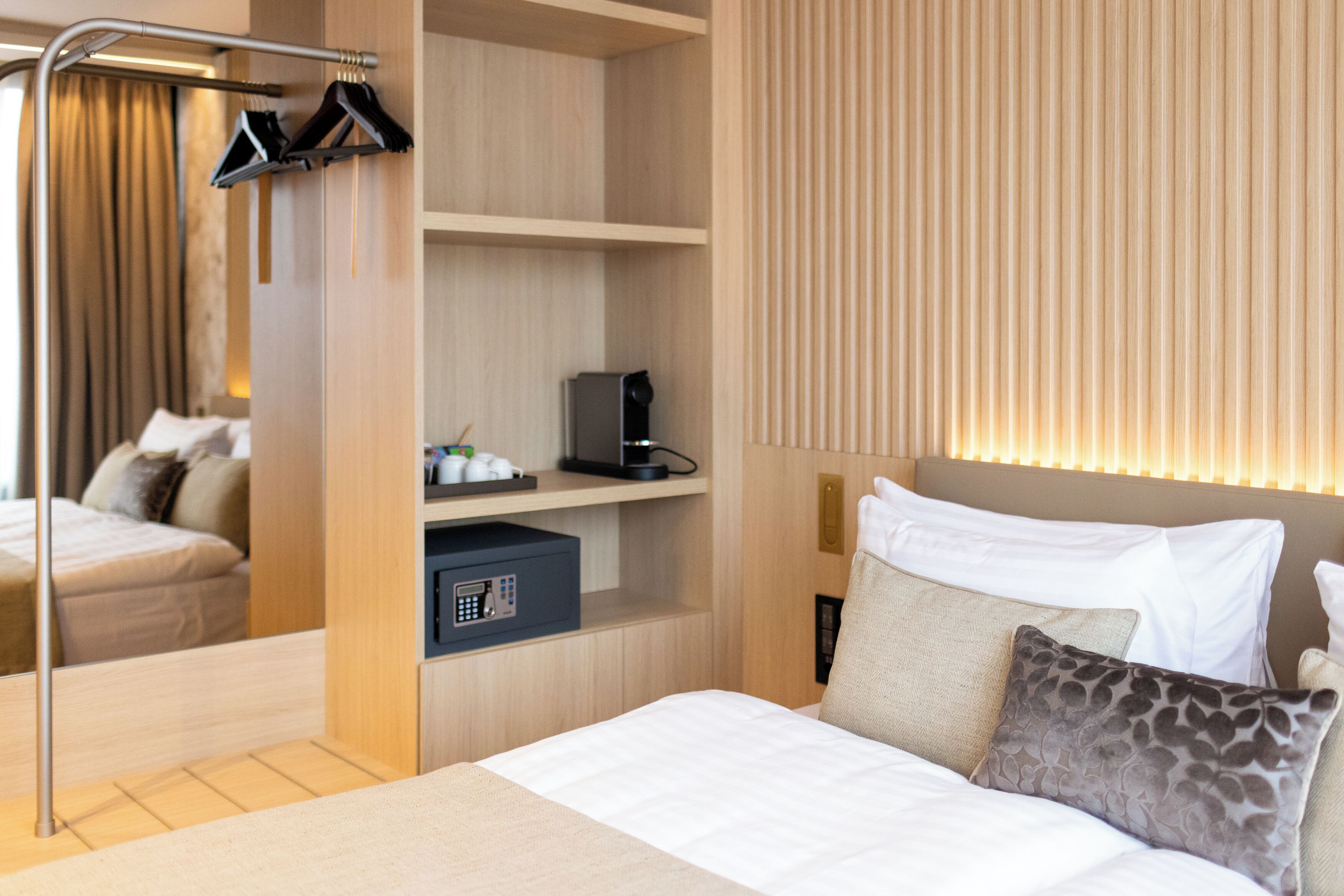 Ein Hotelzimmer mit Bett, Kleiderschrank, Schreibtisch mit Computer und Spiegel.