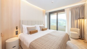 Une chambre d’hôtel moderne, dotée d’un grand lit, d’une table de chevet, d’une chaise et offrant une vue sur l’extérieur.