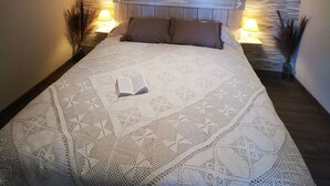Un dormitorio con una cama grande, una pared con textura, un aplique decorativo y dos lámparas de noche.