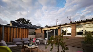 Un patio con mobiliario exterior, una mesa y una planta en maceta.