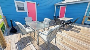 A blue house with a deck, a table, chairs, and a lamp.