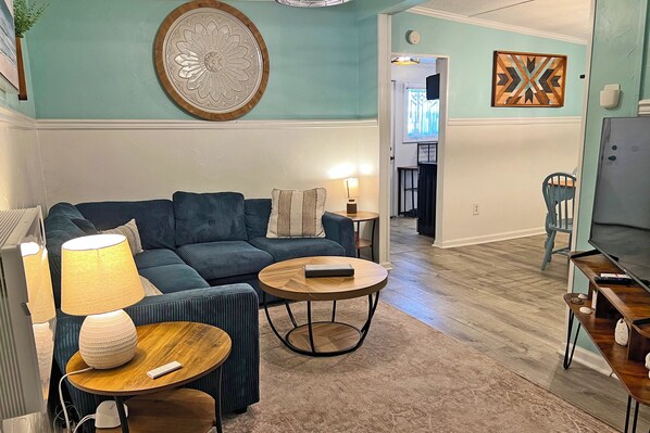 A living room with a sofa, two side tables, a lamp, and a television.
