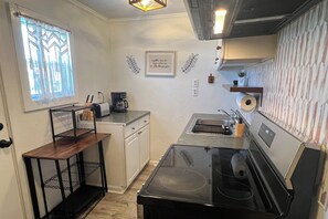 A compact kitchen with a stove, sink, and a window with a view.