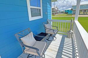 A blue house with a porch featuring two chairs and a small table.
