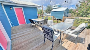 A wooden deck with outdoor furniture, a blue shed, and a red door.