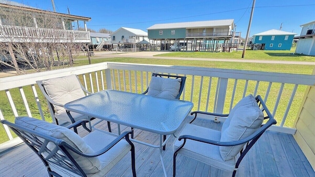 A deck with a glass-top table and four chairs, surrounded by a white railing. - Auralee Unit 1 - Beach Access - Island Realty (Grand Isle)