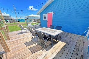 A deck with outdoor furniture, a blue building with a pink door, and a clear sky.