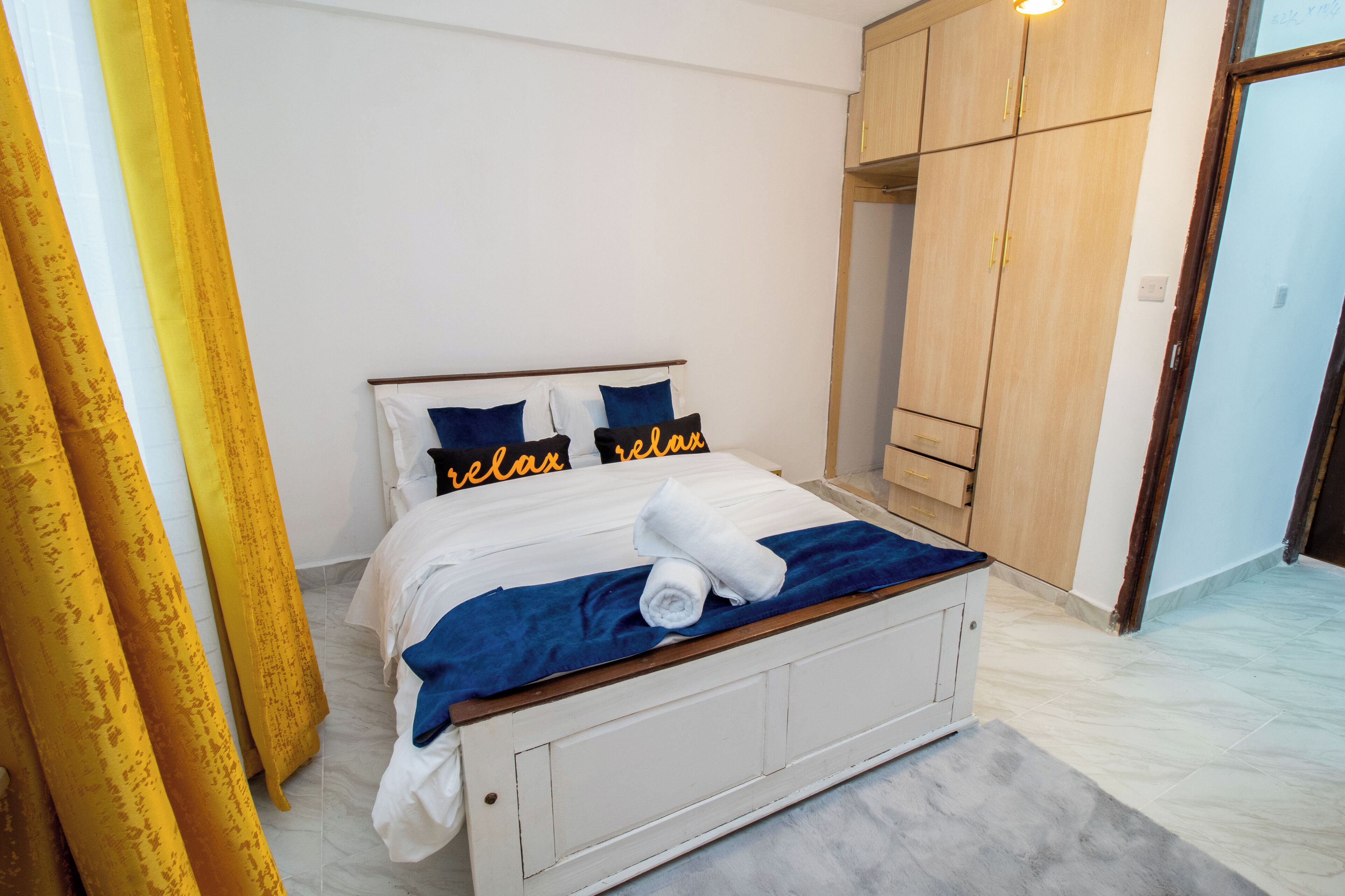 Una camera da letto con un letto, cuscini, una coperta e un armadio.