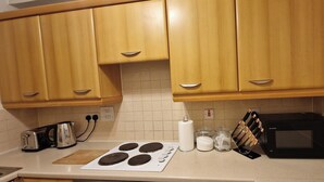 Una cucina con mobili in legno, un fornello, un tostapane, un forno a microonde e un portacoltelli.