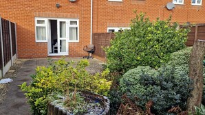 Una casa in mattoni con un piccolo giardino, una recinzione in legno e un'apertura che dà su una stanza.
