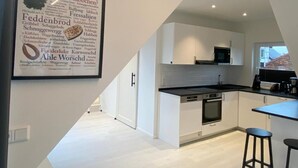 A modern kitchen with white cabinetry, a black countertop, and a built-in oven. - Spacious modern DG apartment Schloofschdubb near Kassel 70 sqm (Fuldatal)