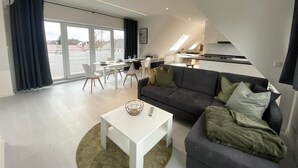 A modern living room with a sofa, coffee table, and dining area. - Spacious modern DG apartment Schloofschdubb near Kassel 70 sqm (Fuldatal)