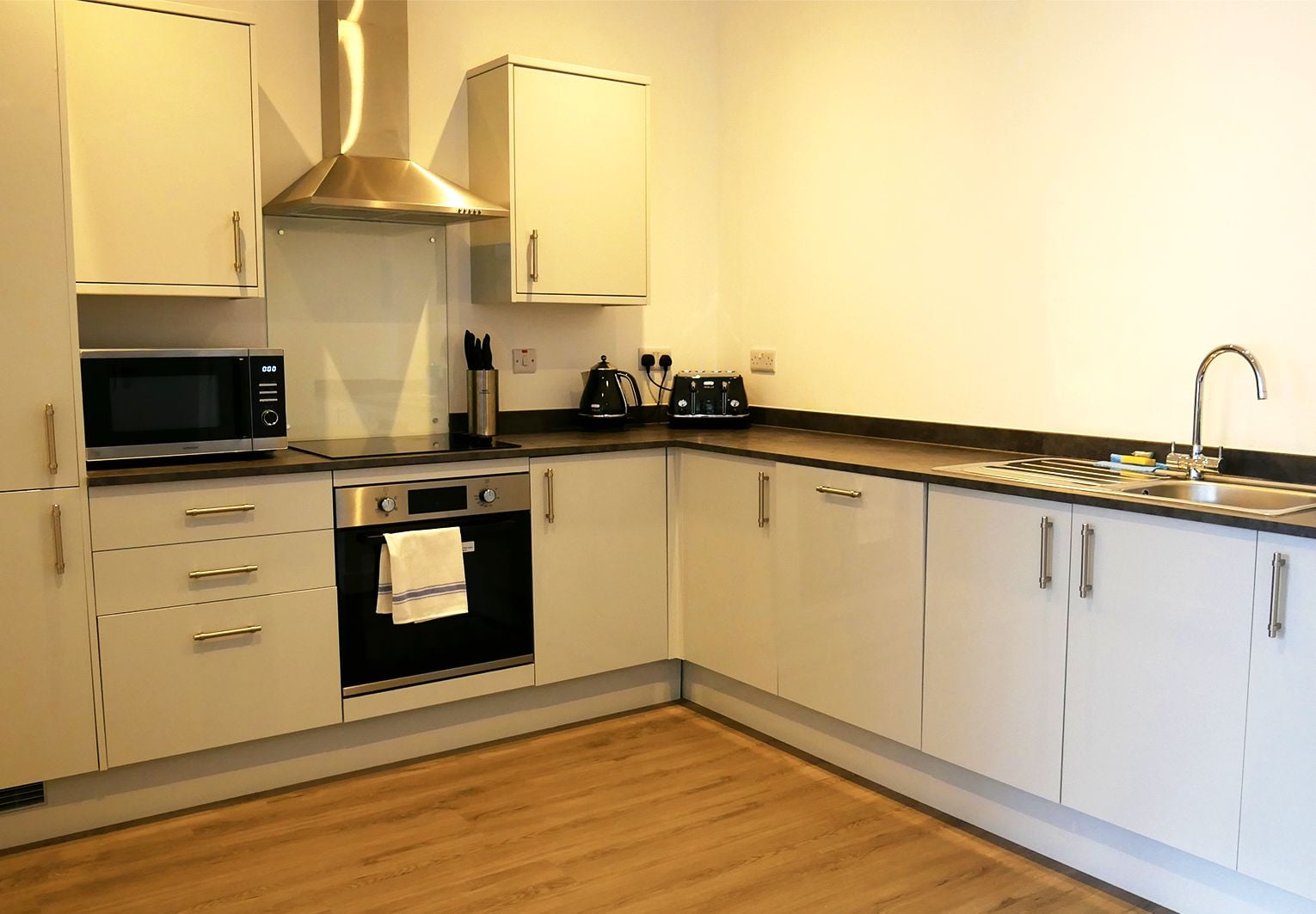 A modern kitchen with a microwave, oven, and sink.