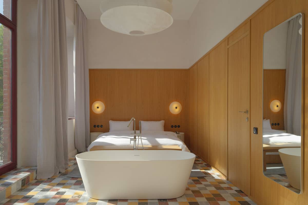 A modern bedroom with a large bathtub, wooden paneling, and a large mirror.