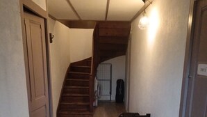 Un couloir étroit avec un escalier en bois menant à une buanderie.