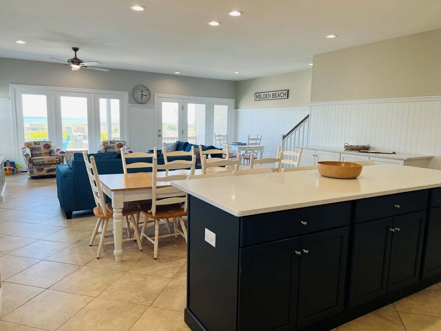 A spacious living area with a dining table, blue sofa, and a kitchen island.
