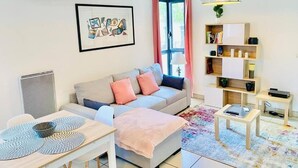 A modern living room with a sofa, a dining table, and a bookshelf.