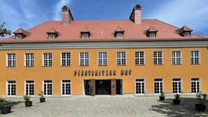 A yellow building with the sign "PIETERSATZ KOF" and a cobblestone courtyard with potted plants. - Piesteritzer Hof - Hotel Garni (Lutherstadt Wittenberg)
