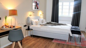 A modern bedroom with a white bed, a desk with a lamp, a chair, and a window with curtains. - Piesteritzer Hof - Hotel Garni (Lutherstadt Wittenberg)