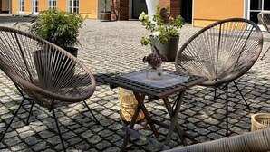 A hotel exterior with a yellow facade, multiple windows, and outdoor seating with wicker chairs and a table. - Piesteritzer Hof - Hotel Garni (Lutherstadt Wittenberg)